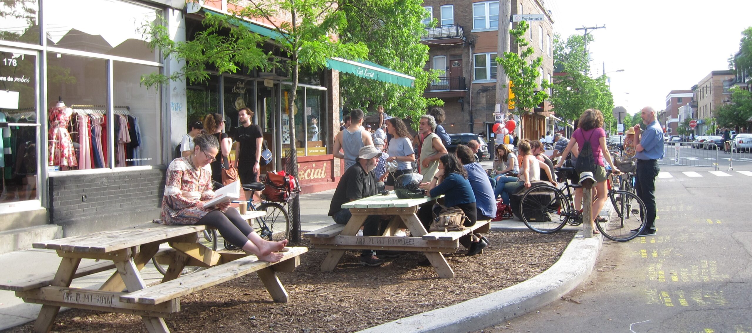 Photo d'une terrasse de café extérieure avec plusieurs tables et quelques personnes